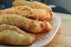 Pile of delicious breadsticks on plate